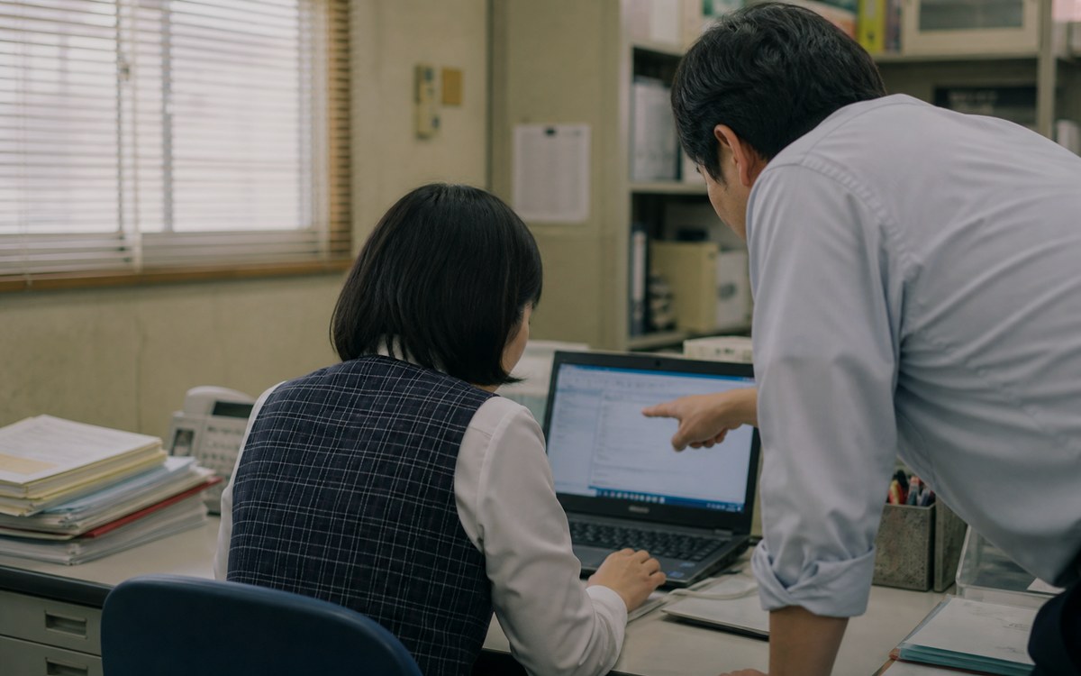 事務所で、担当者のパソコン画面を一緒に見ながら操作を確認している様子